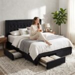 Woman relaxing on a custom black velvet storage bed frame with metal structure and under-bed drawers. Wholesale furniture by MMK Trade Inc.