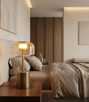 brass cylindrical base crackle glass table lamp on wooden nightstand in luxury hotel bedroom suite